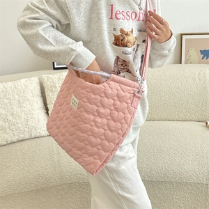 Détail du sac matelassé rose clair avec coutures en cœur et poignée tressée
