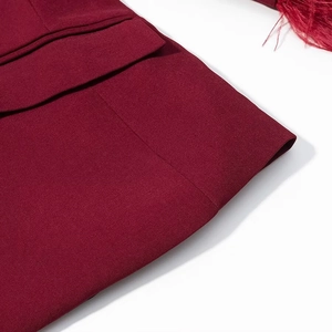 Close-up of wine red blazer featuring elegant feather trim cuffs and fine twill texture
