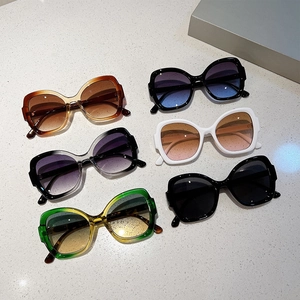 Flat lay of oversized butterfly sunglasses in various colors on a white stone texture