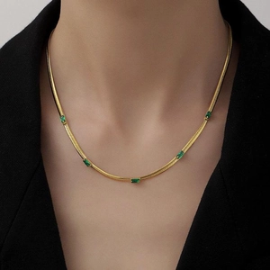 Elegante collana a catena serpente dorata con cinque pietre verde smeraldo su una modella
