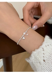 Detailed close-up of a silver starfish and shell bracelet with white pearls