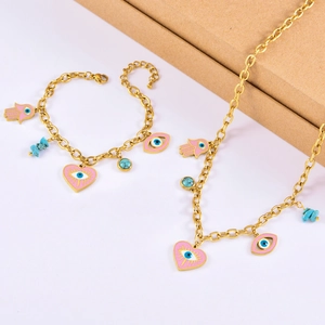Detailed view of pink heart evil eye and hamsa hand pendants on golden jewelry