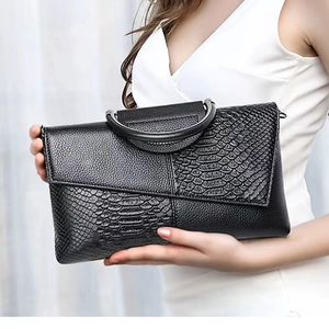 Close-up of black crocodile pattern handbag featuring a round metal top handle