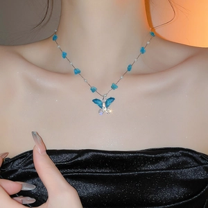 Collar de mariposa azul con piedras de cristal y perlas usado por modelo en la clavícula