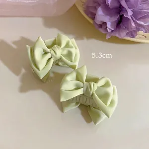 Detail of 5.3cm satin ribbon bow hair claw clips in soft green silk fabric for women