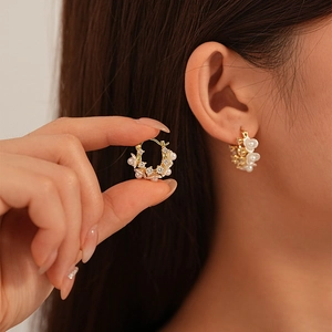Orecchini a cerchio a fiore in oro con perle e zirconi indossati da una modella