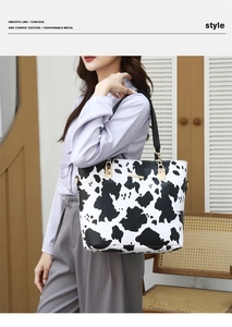 Detail of cow print tote bag featuring golden hardware and smooth faux leather texture