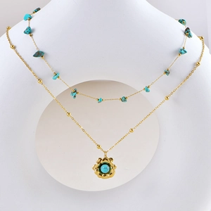 Dettaglio di una collana bohémien a doppio strato dorata con pietra turchese e fiori