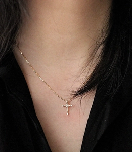 Close-up of a gold S925 sterling silver cross necklace with pavé zircons on a model