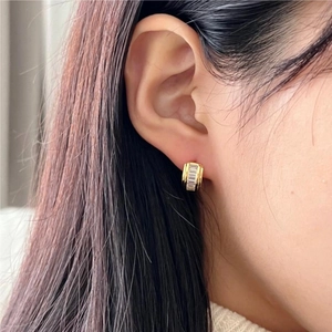 Golden sterling silver hoop earrings with cubic zirconia shown on model's ear