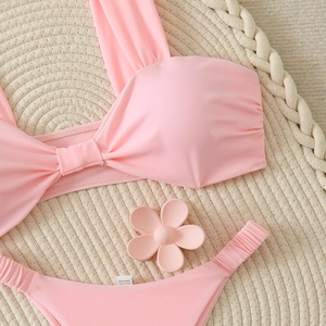 Détail de la matière du bikini rose montrant l'étiquette sur fond de plage tressé