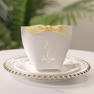 Minimalist wedding candy box with golden tulip and yellow ribbon on a white plate