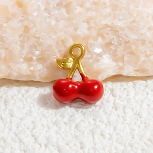 Detailed macro shot of a cherry pendant with bright red enamel and golden metal branch