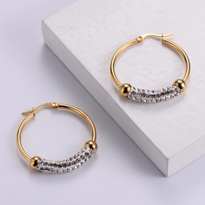 Elegant gold hoop earrings with zircon pavé crystals shown on minimalist white blocks