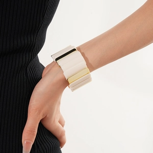 Close-up of wide segmented elastic bracelet in beige and gold on woman wrist