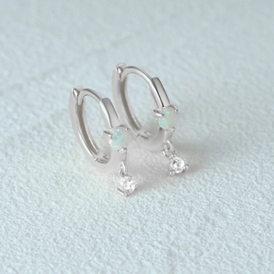 Macro shot of silver hoop earrings with white opal stones and sparkling zircon charms