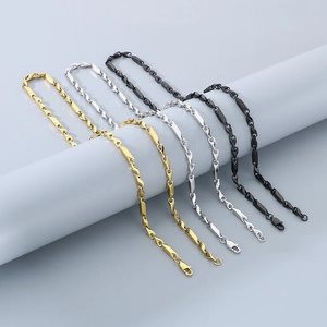 Close-up of modern geometric link chains in gold, silver, and black stainless steel