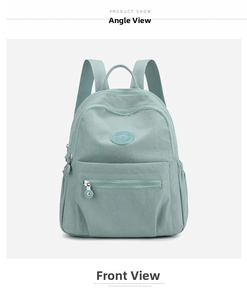 Front view of light green water-resistant nylon backpack with zip pocket and round badge