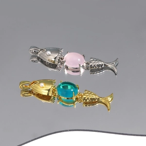 Detail view of gold and silver fish pendants with colorful gemstones and pearls