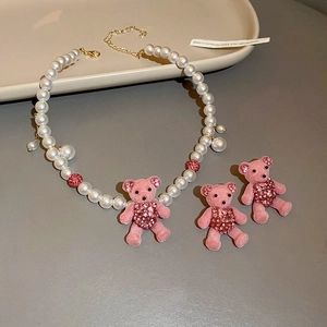 Close-up of pink flocked bear earrings and pearl necklace set with sparkling rhinestones
