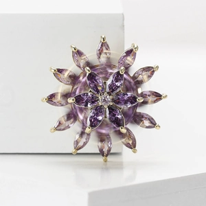 Detailed view of layered rotating snowflake brooch with purple and pink cubic zirconia