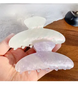 Detail of white and purple pearlescent acrylic hair claws with elegant mica texture finish