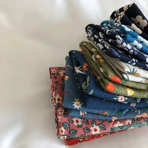 Close-up of stacked cotton linen bandanas with assorted floral patterns and vibrant colors
