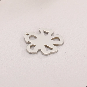 Macro shot of silver hollow rose petal pendant with hanging hole on soft fabric