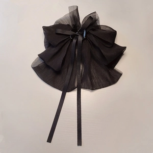 Close-up of black oversized bow hair claw clip with long chiffon ribbons and square buckle