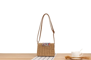 Détail d'un petit sac en paille tisseé avec des perles colorées et une bandoulière en cuir
