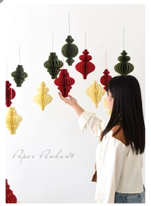 Hanging honeycomb paper pendants in red, green, and beige for festive holiday decoration
