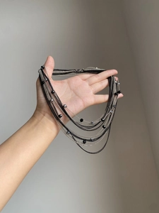 Dettaglio di una collana gotica a più strati con perle nere e accenti argentati