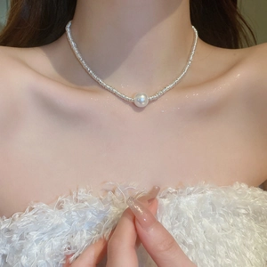 Close-up of minimalist silver bead necklace with a white pearl on a female model