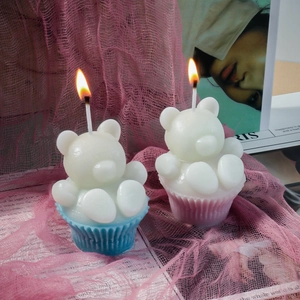 Bougies oursons 3D créatives en moule à muffin rose et bleu allumées dans un décor cosy