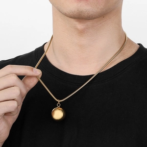Detailed view of a gold snake chain necklace with a smooth polished spherical pendant