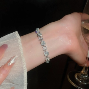 Détail macro du bracelet argenté avec pierres œil-de-chat vertes et fleurs en zircon