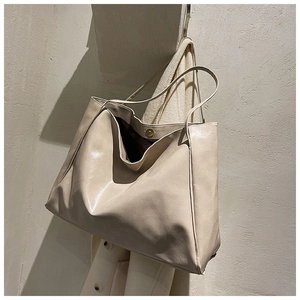 Detail of minimalist cream leather tote bag featuring a magnetic clasp and fine texture
