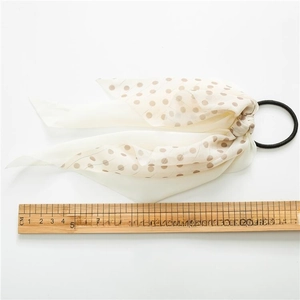 Beige polka dot bow hair scrunchie with streamers, 24cm length on white background