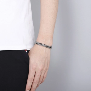 Gros plan d'un bracelet en acier inoxydable argenté tressé sur un poignet d'homme punk
