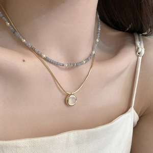 Detail of layered gold snake chain with moonstone pendant and pearl stone choker