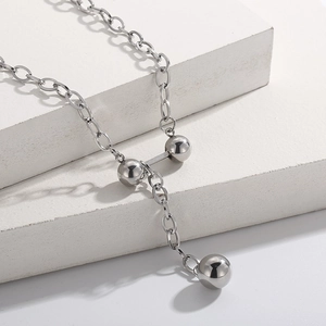 Détail d'un collier à perles en acier inoxydable argenté sur un socle en pierre