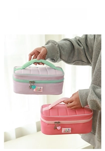Detailed view of quilted makeup bag with heart zipper charm and wide top handle strap