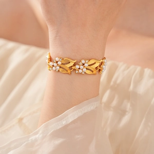 Close-up of a golden leaf bracelet with white pearls and small diamonds on a wrist