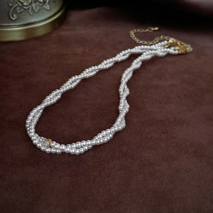 Elegant double-layered pearl choker with zircon pendant on dark velvet background