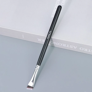 Détail du pinceau à sourcils biseauté avec poils synthétiques et manche en bois noir