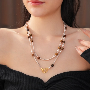 Gros plan d'un collier à double rangée avec perles blanches et pierres d'oeil de tigre