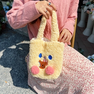 Detail of cute beige plush tote bag with bear embroidery and soft pink pom pom blush
