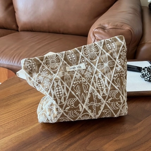 Detail of embroidered white diamond pattern on brown linen cotton cosmetic bag