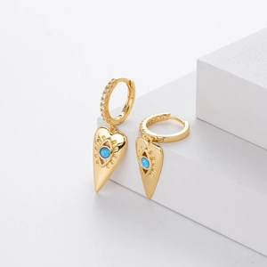 Detailed macro view of gold-plated evil eye hoop earrings with blue heart-shaped charms