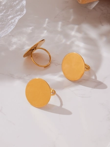 Trois bagues circulaires plaquées or 18k disposées sur un fond à texture de marbre